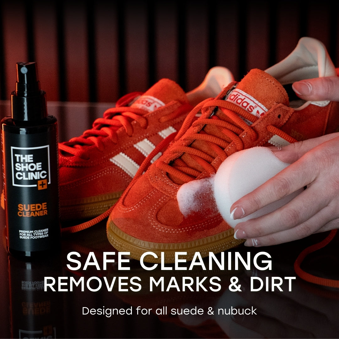 Orange sneakers being cleaned with a sponge next to The Shoe Clinic suede cleaner bottle.