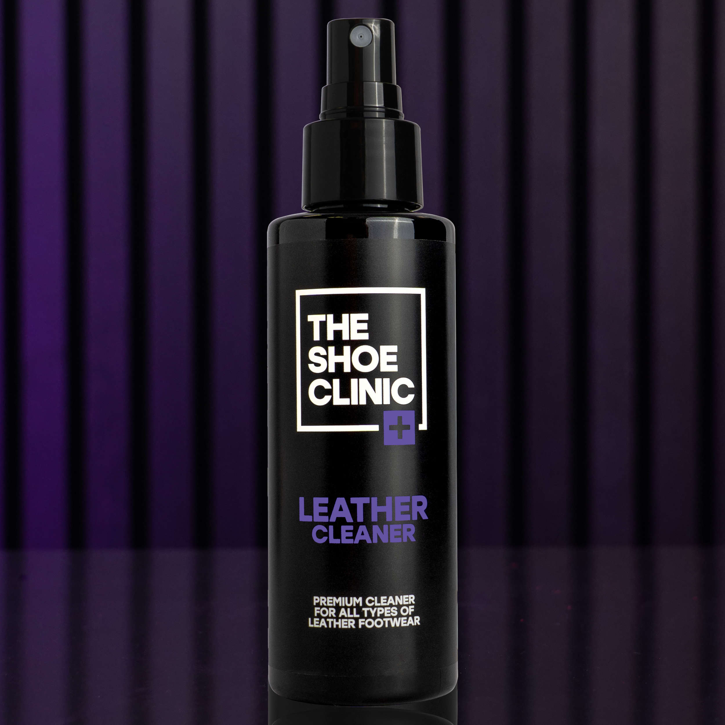 Black bottle of The Shoe Clinic leather cleaner on a purple striped background